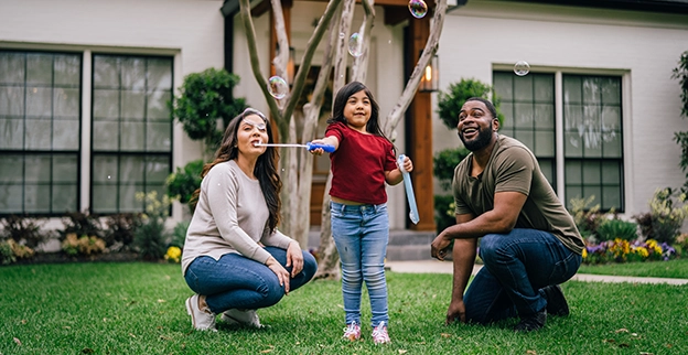 A family in the front yard of their home with a freshly painted exterior.