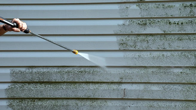 A picture of a power washer removing dirt and grime from siding.