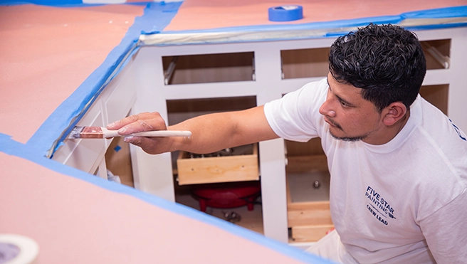 Five Star Painting professional painting a kitchen cabinet.