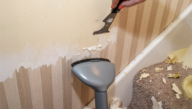 Steaming wallpaper off of a wall.